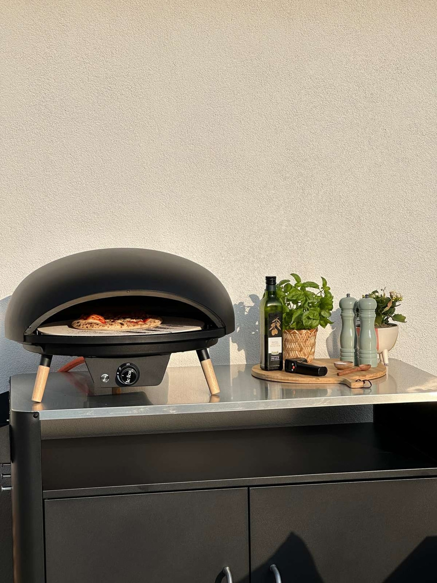 Pizzaofen mit Zutaten auf einer Metalloberfläche im Freien