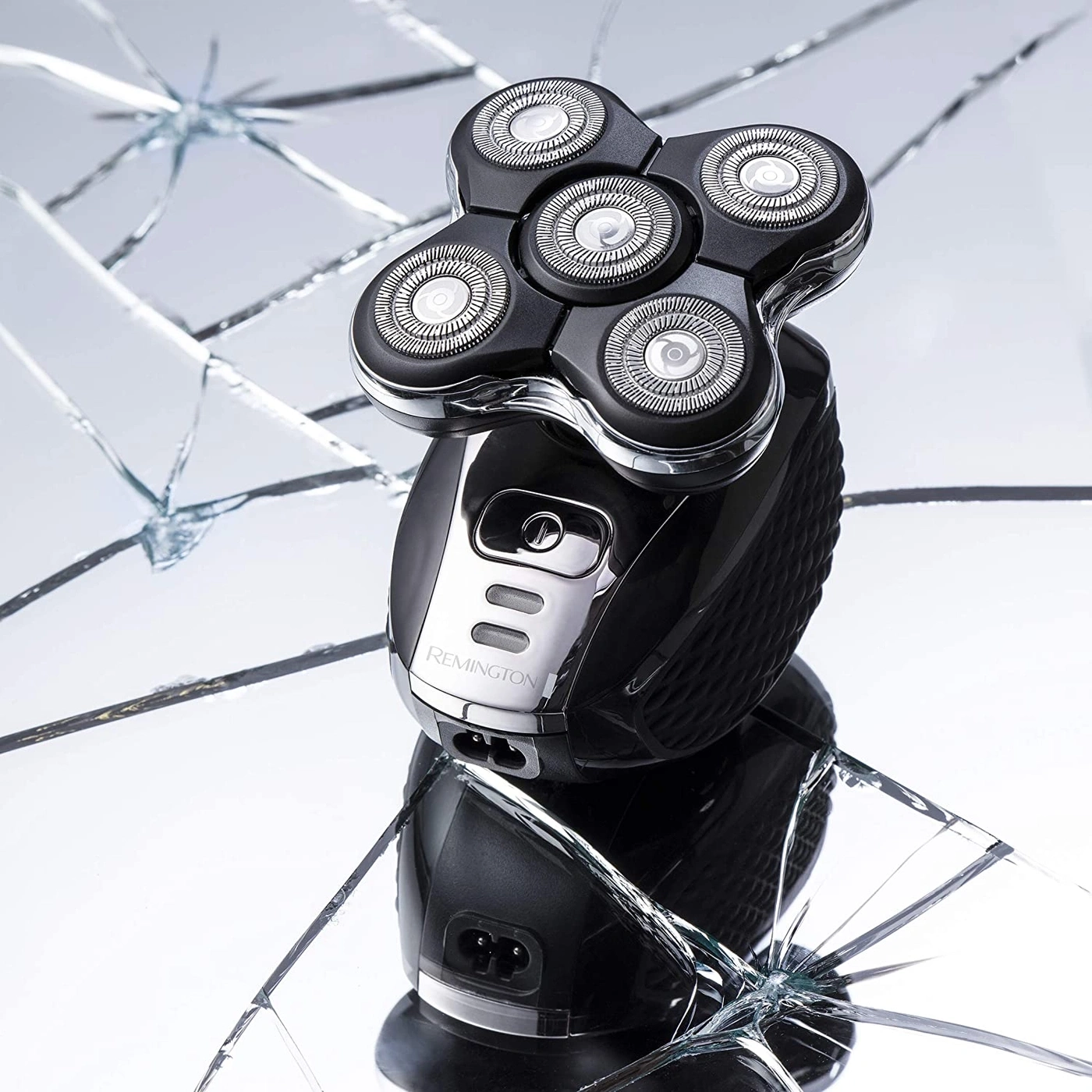 Elektrischer Rasierer auf zerbrochenem Glas, Produktfotografie, Remington Rasierer, schwarz