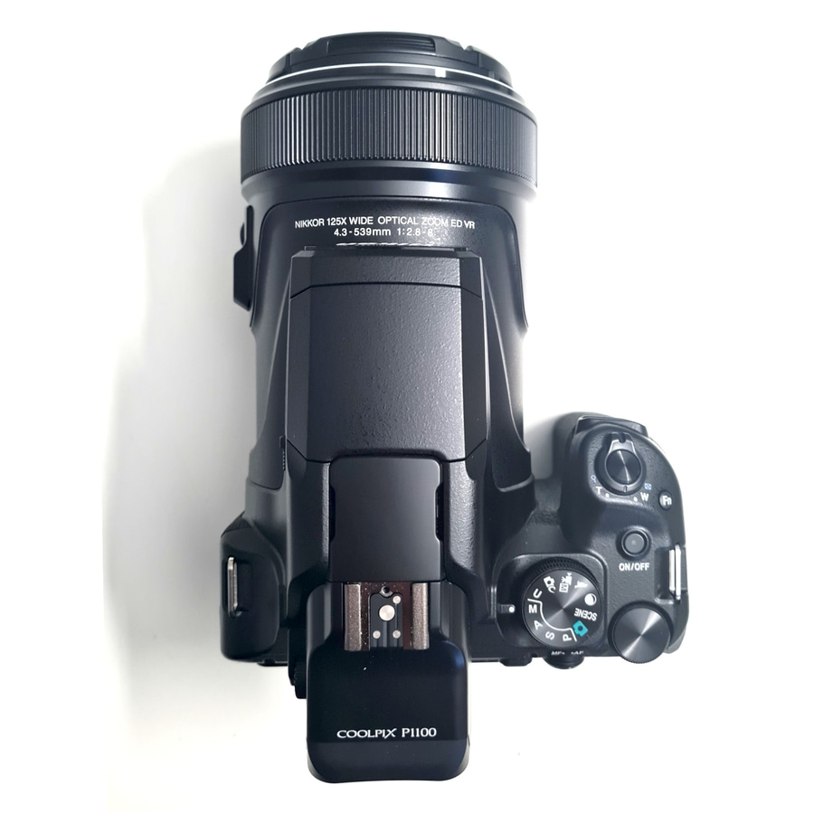 Eine schwarze Nikon Coolpix P1100 Digitalkamera mit großem Objektiv von oben