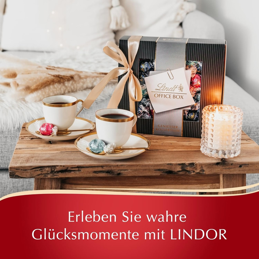 Lindt Office Box mit Kaffeetassen und Kerze auf Holztisch.
