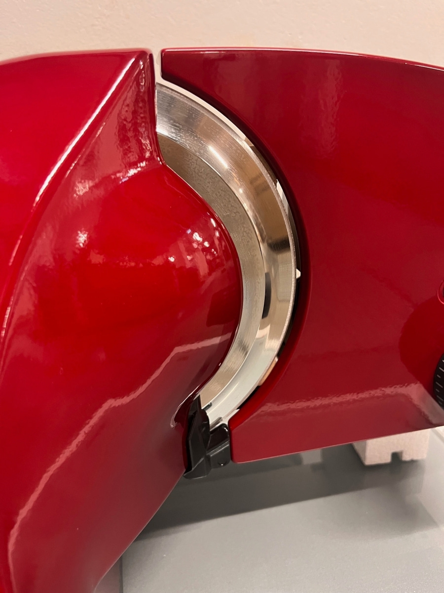 Nahaufnahme eines roten Fleischschneiders mit glänzender Oberfläche und Klinge