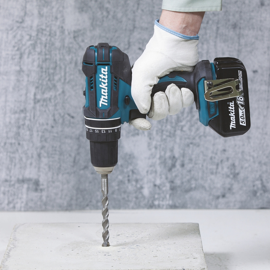 Person bohrt mit Makita-Bohrmaschine in Betonblock, Nahaufnahme, Handschuhe