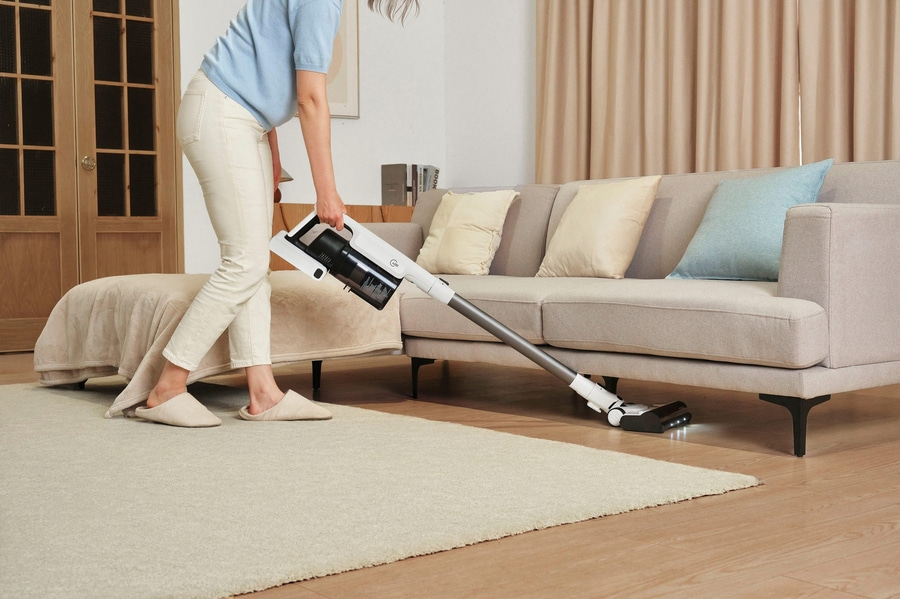 Person saugt Teppich mit Staubsauger im Wohnzimmer, Hausarbeit