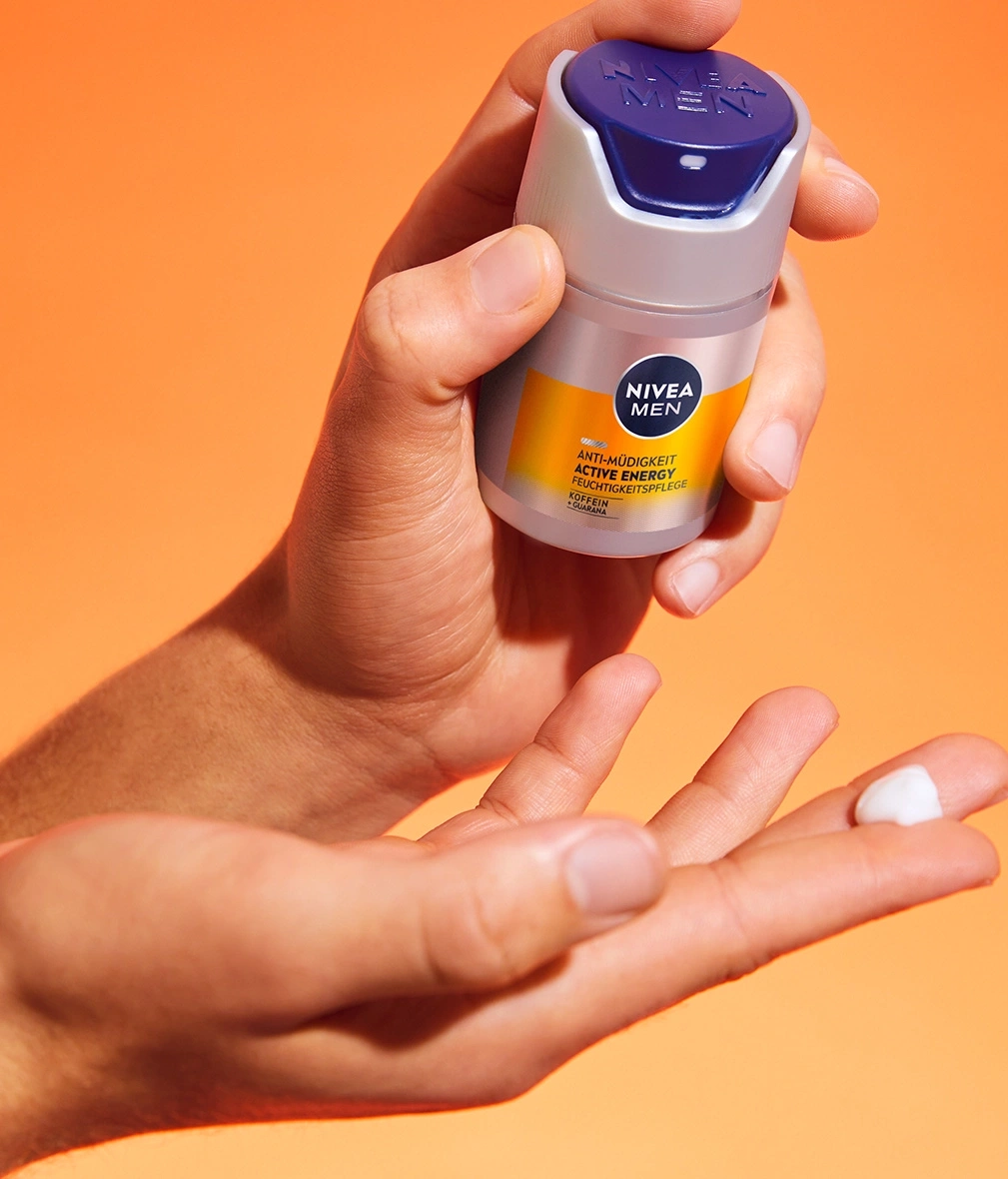 Mann hält Nivea Men Creme in der Hand, orangefarbener Hintergrund, Hautpflege