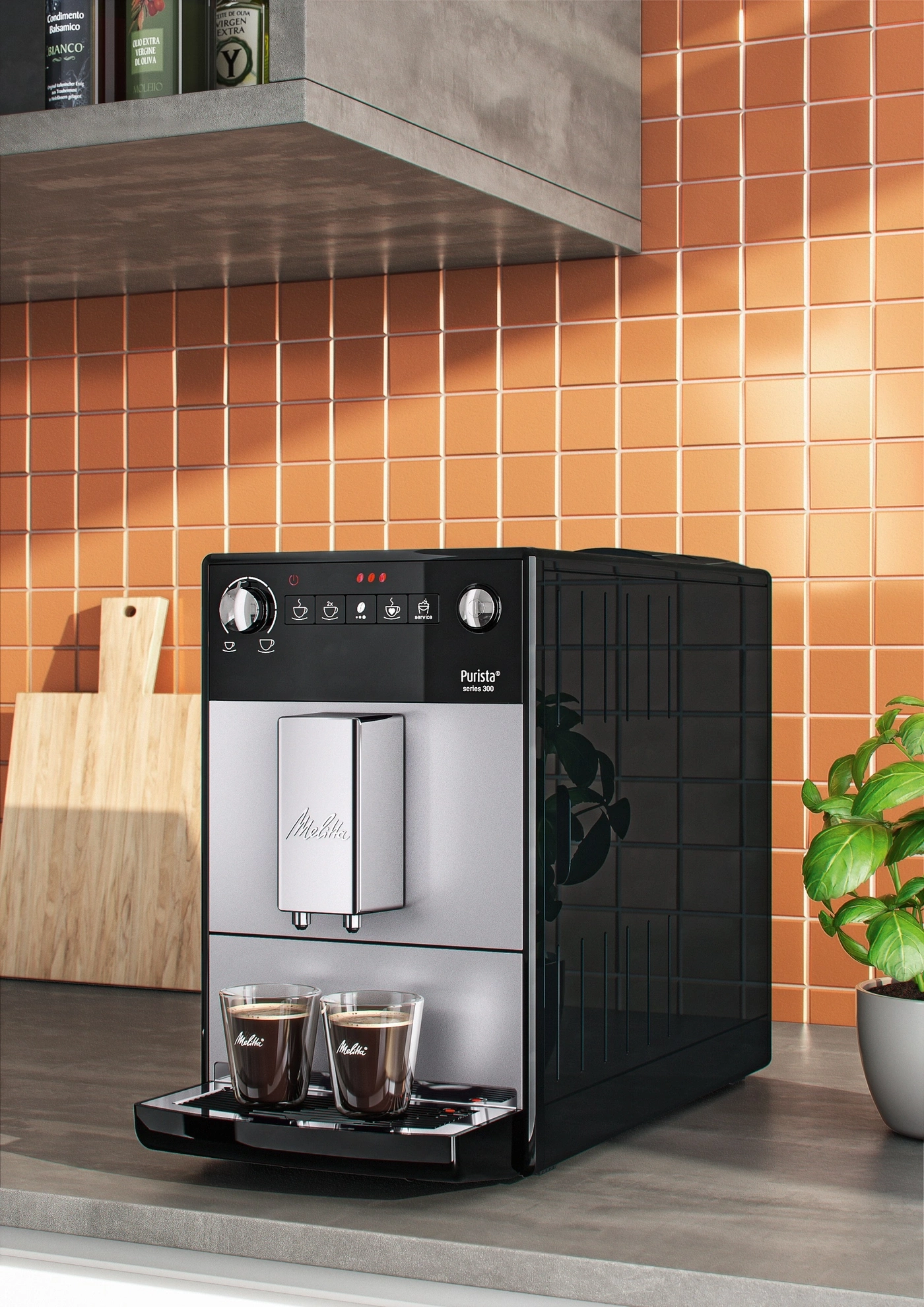 Kaffeemaschine mit zwei Tassen Kaffee auf einer Küchenarbeitsplatte mit Fliesen und einer Pflanze.