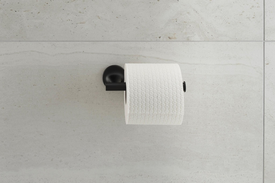 Schwarzer Toilettenpapierhalter mit weißem Papier an einer Steinwand.