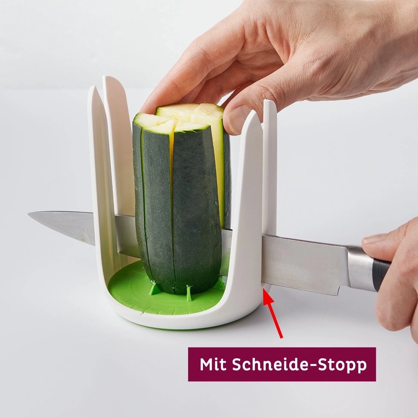 Zucchini wird mit einem Messer und einer Schneidehilfe geschnitten. Die Hand hält das Gemüse.