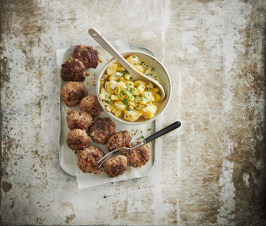 Fleischbällchen mit Kartoffelsalat auf einem Tablett, rustikal