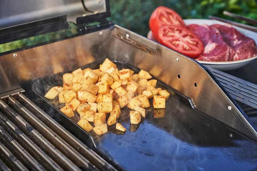 Kartoffeln auf dem Grill, Tomaten und Fleisch in einer Schüssel.