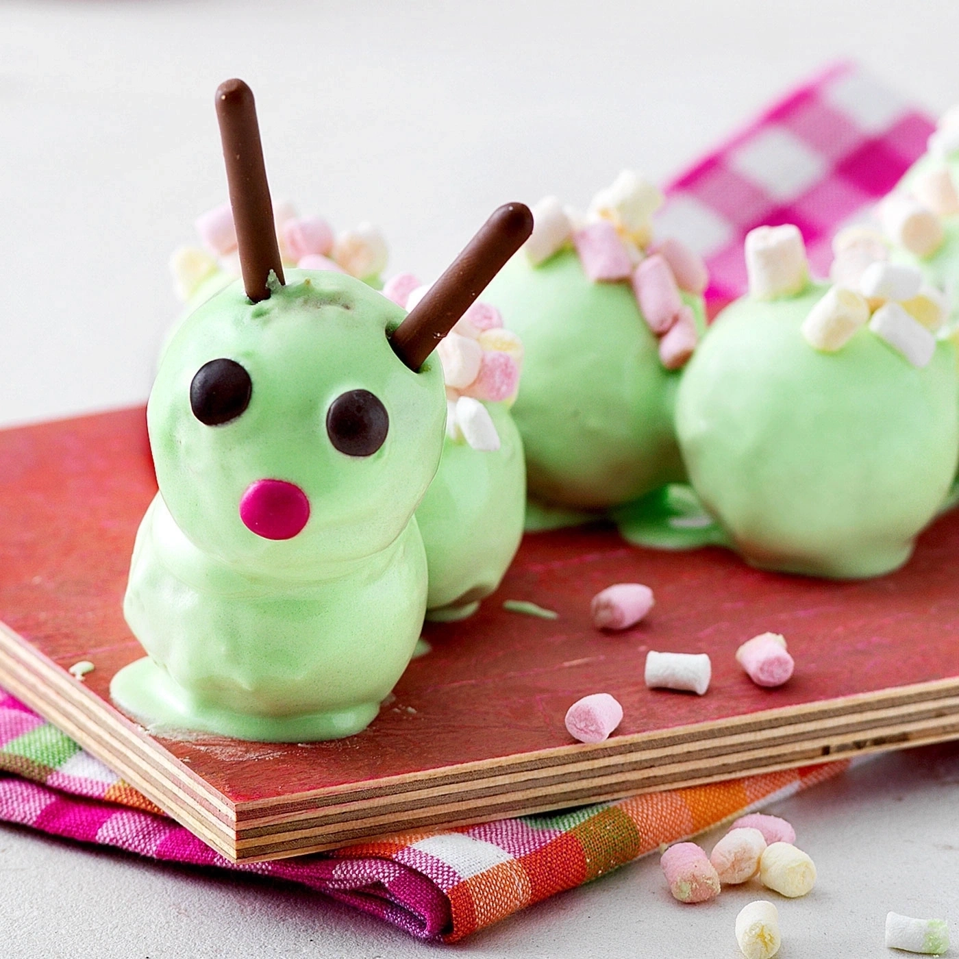 Grüne Raupen-Desserts mit Schokoladen-Antennen und Marshmallows auf Holzbrett