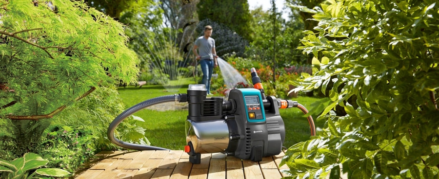 Gartenpumpe mit Person, die einen Rasen bewässert, umgeben von Grün