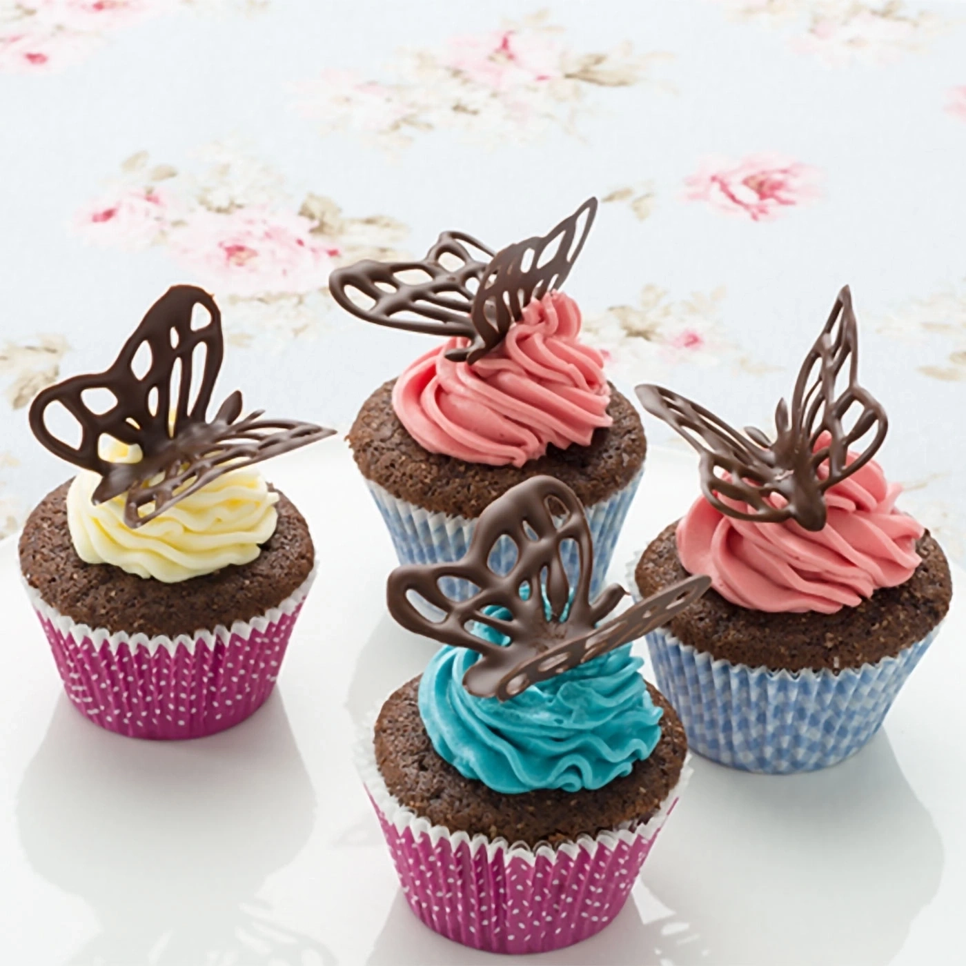 Schokoladen-Cupcakes mit Schmetterlingen, rosa, blau und gelb glasiert