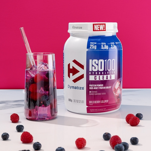 Dymatize ISO100 Protein-Pulver mit Beeren, Glas und Früchten auf weißem Tisch