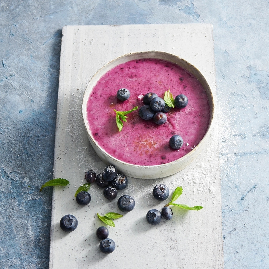 Blaubeer-Smoothie mit frischen Blaubeeren und Minze auf einem Brett