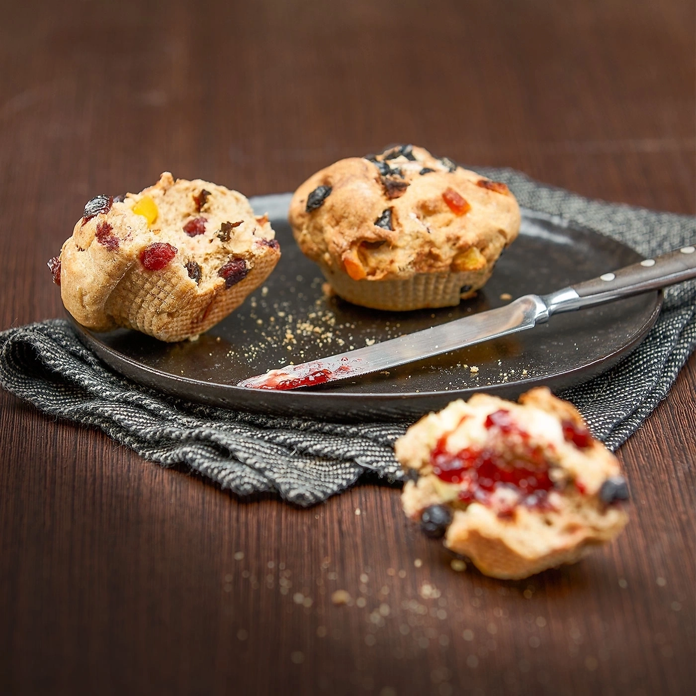 Muffins mit Früchten auf einem Teller mit Messer und Marmelade