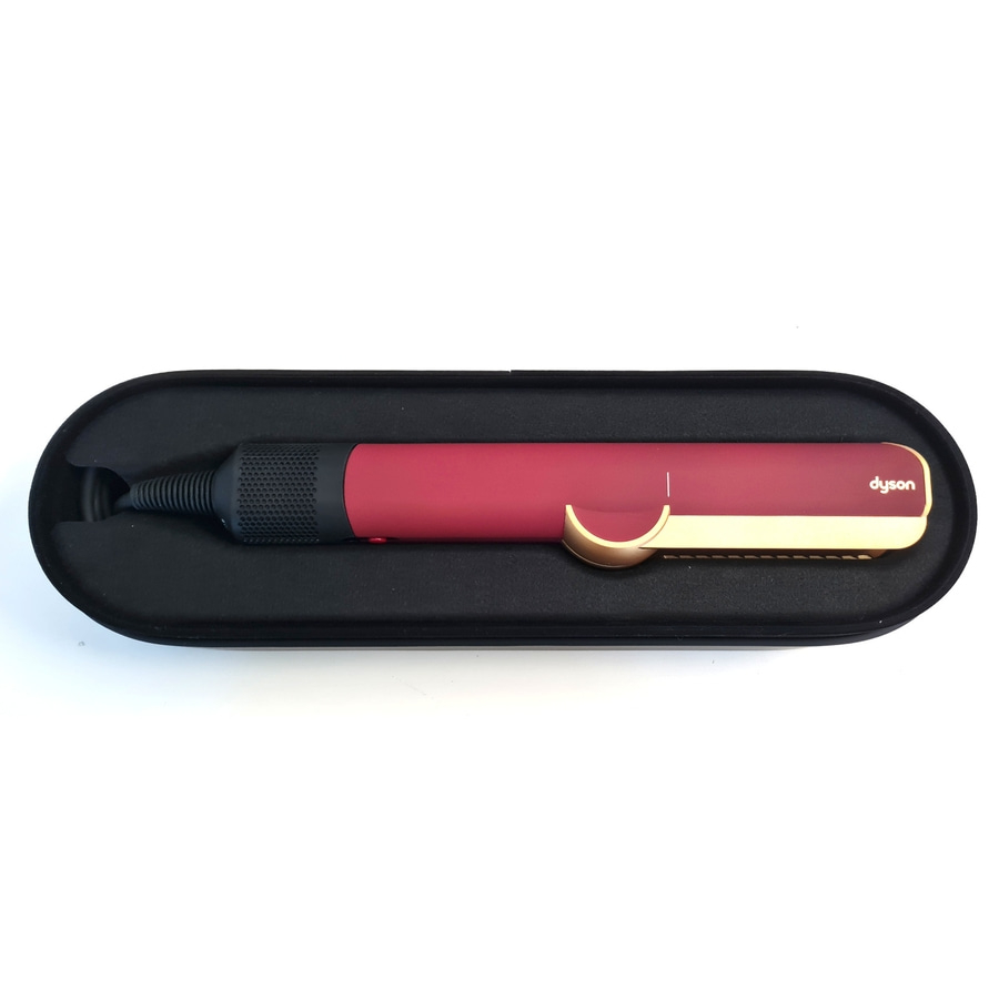 Ein roter Dyson-Haarglätter mit goldenen Akzenten in einer schwarzen Aufbewahrungsschale.
