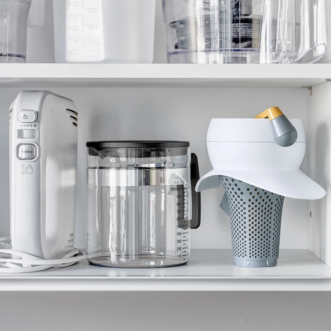 Küchenschrank mit Mixer, Glasbehälter und Filtergerät. Weiße Geräte.