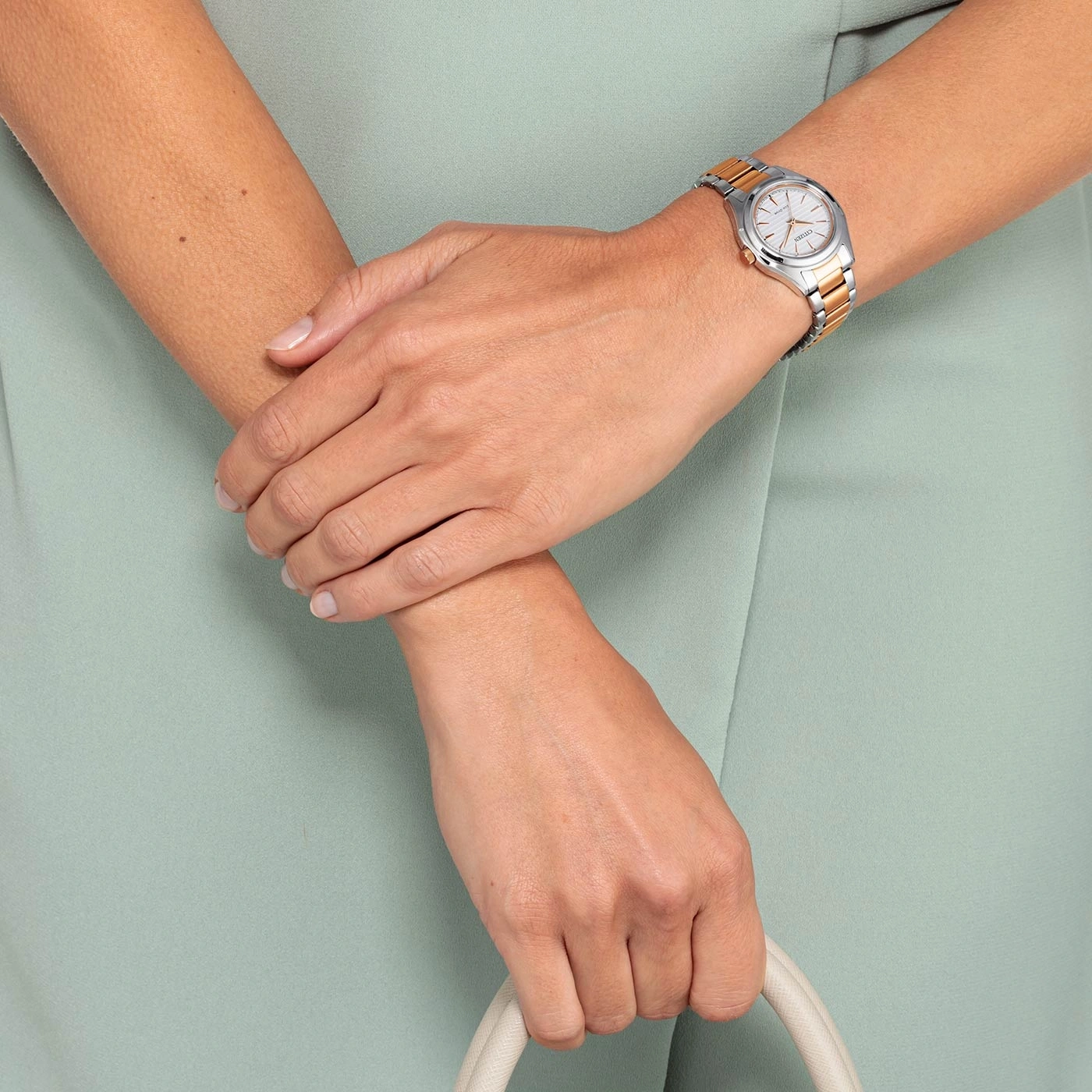 Frau mit Uhr und Handtasche, vor hellgrünem Hintergrund