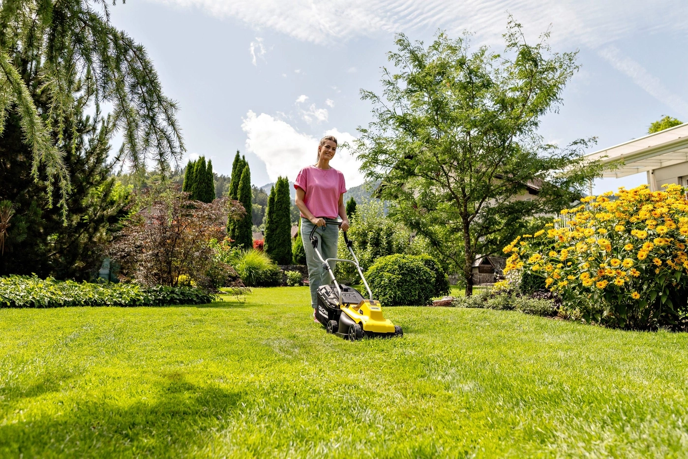 Eine Frau mit einem Rasenmäher im Garten