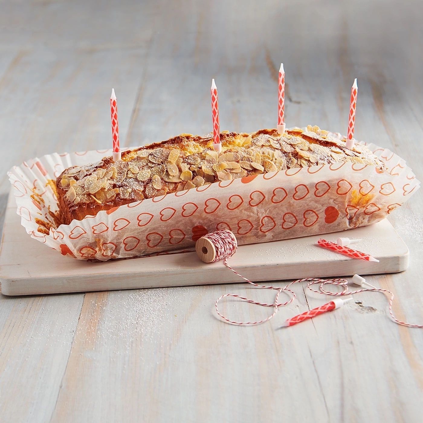 Kuchen mit Mandeln und Kerzen, auf einem Holzbrett, festlich dekoriert.