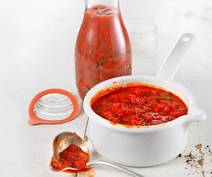 Tomatensauce in Topf, Glas und Löffel. Hausgemachtes Essen, lecker und frisch.