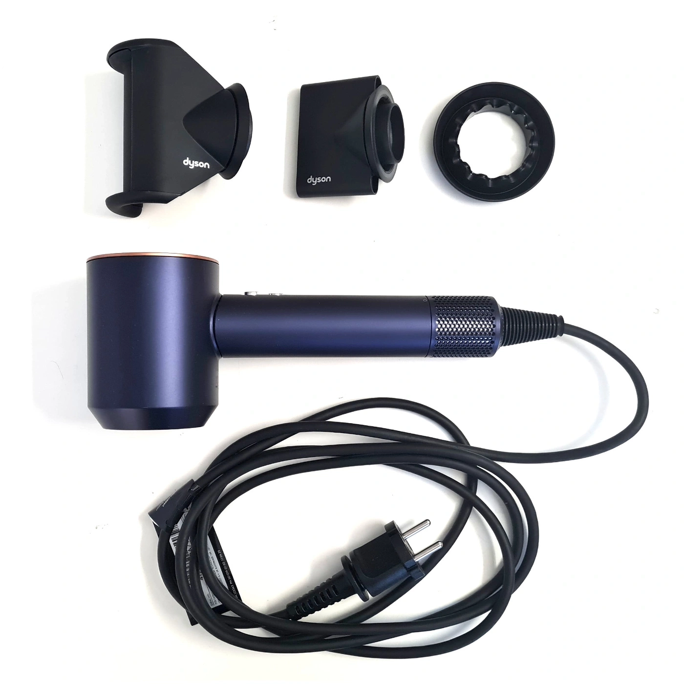 Dyson Haartrockner mit Zubehör und Kabel auf weißem Hintergrund