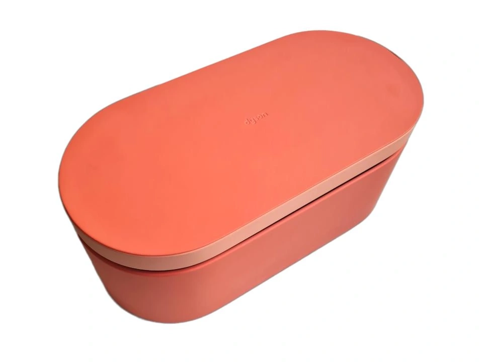 Ein orangefarbener Behälter mit einem helleren Deckel und dem Dyson-Logo.