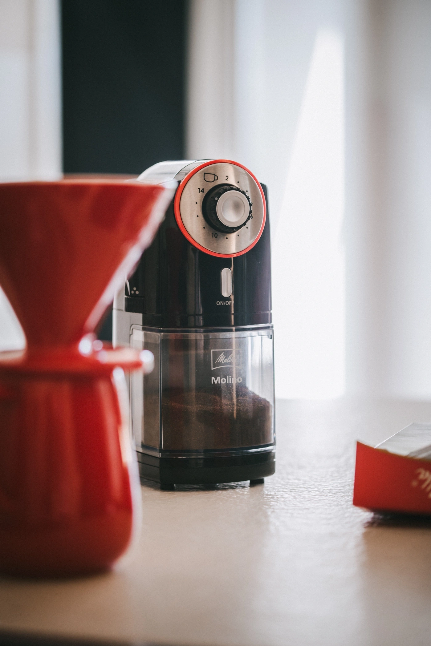 Kaffeemühle mit rotem Filter und Kaffeepulver, Nahaufnahme, Melitta Molino
