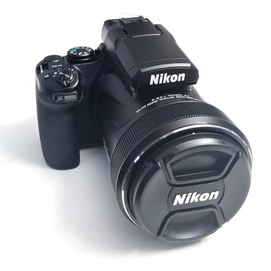 Eine schwarze Nikon-Kamera mit Objektivdeckel und Nikon-Logo auf dem Blitz.