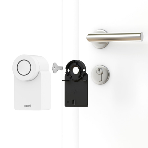 Ein Nuki Smart Lock mit Schlüssel und Montageplatte auf einer weißen Tür.