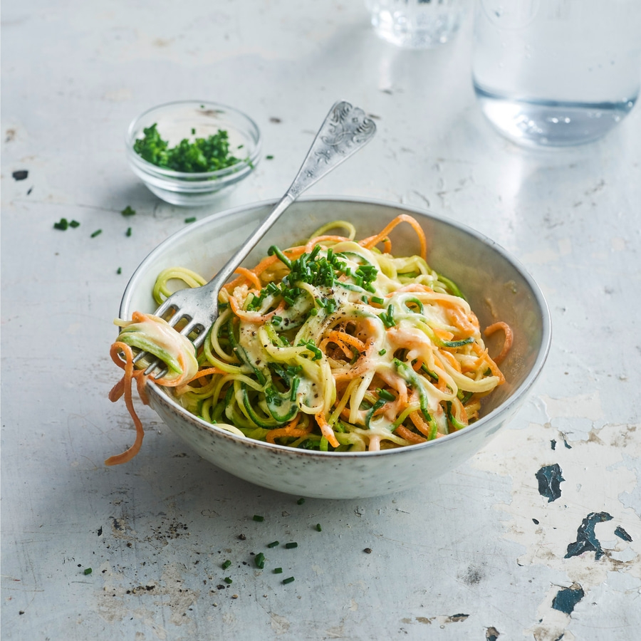 Gemüse-Nudeln mit Sauce und Kräutern in einer Schüssel mit Gabel