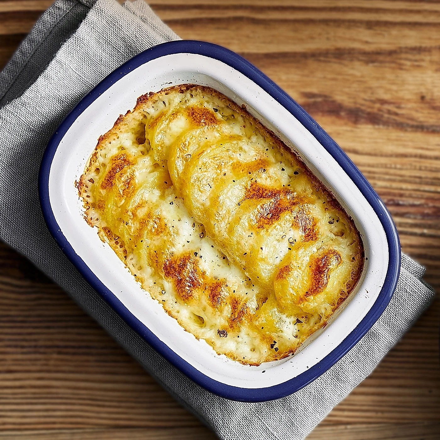 Gratin im Ofen, Käse, Kartoffeln, Auflaufform, Holzuntergrund, Serviette