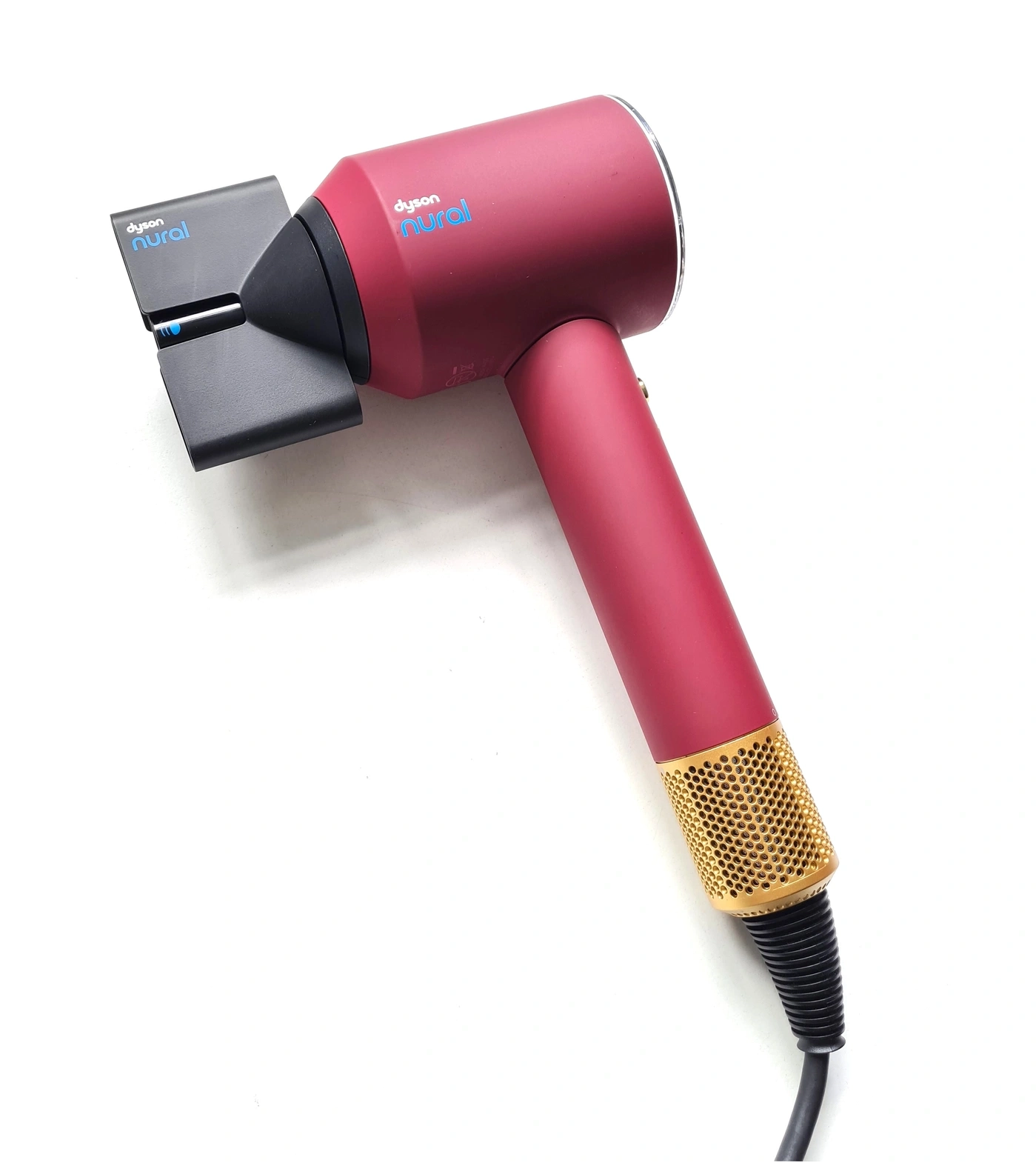 Ein roter Dyson Haartrockner mit goldenem Gitter und einem Aufsatz.