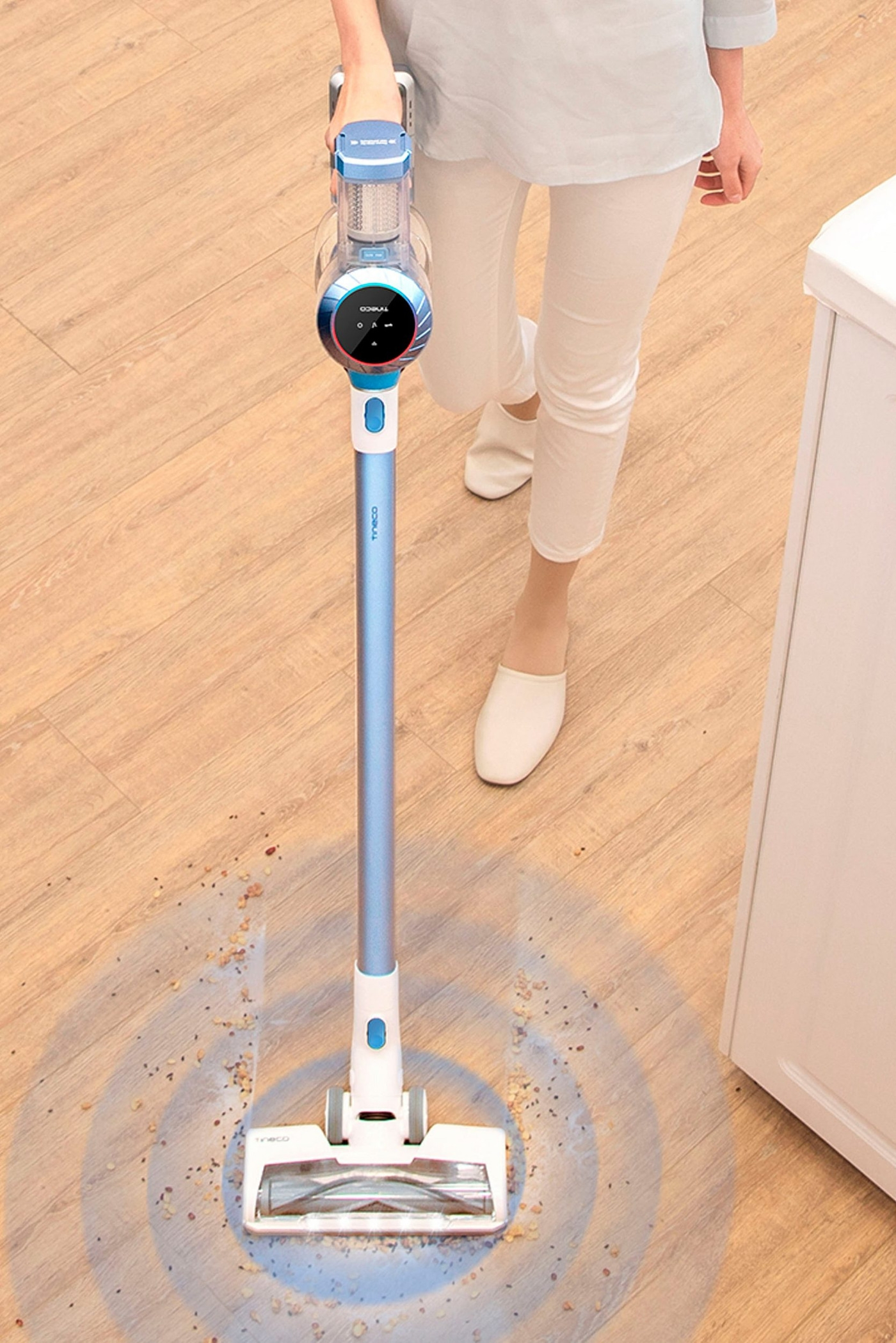 Person, die einen Staubsauger benutzt, um Krümel vom Holzboden zu entfernen.