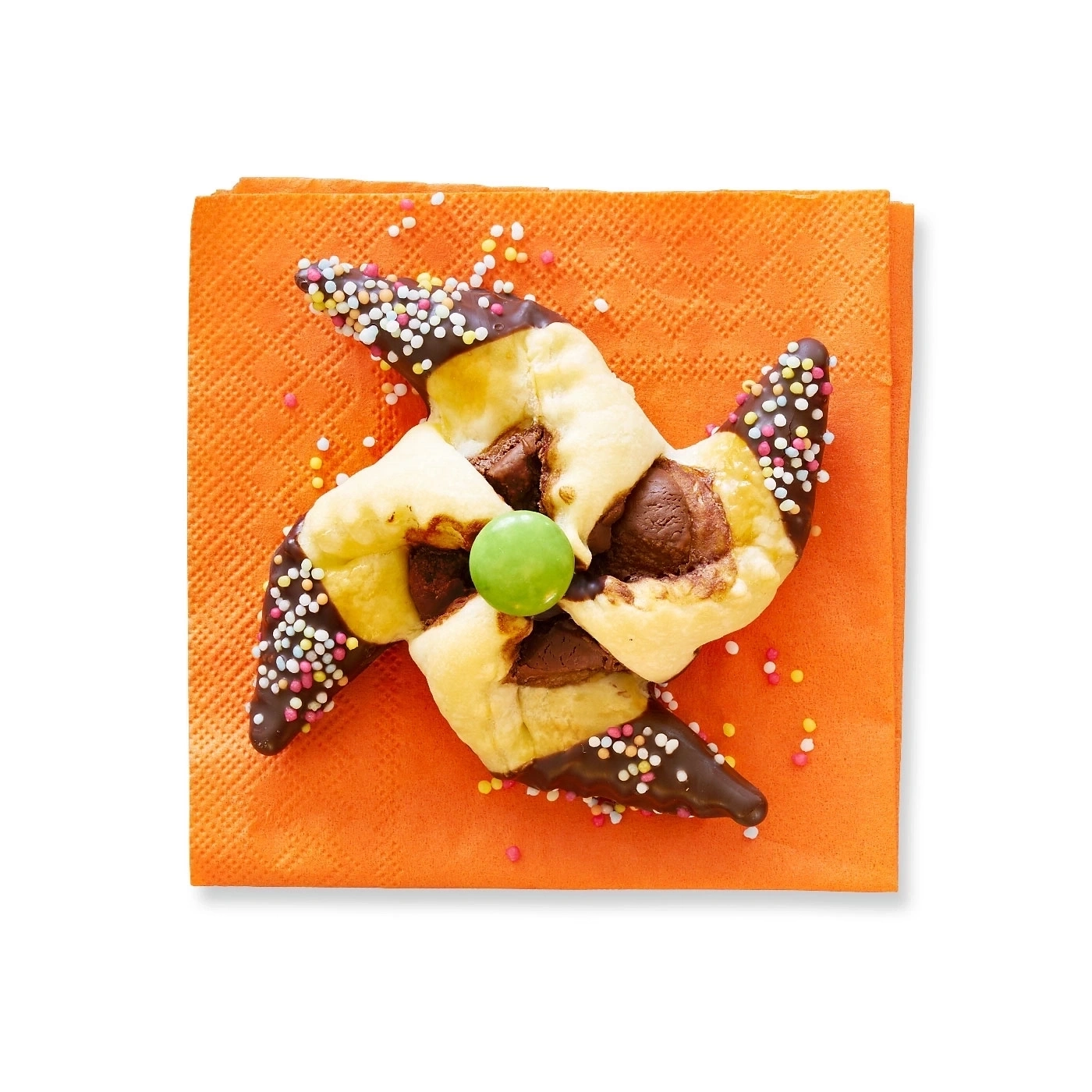 Gebäck mit Schokolade und Streuseln auf orangefarbenem Papier, Nahaufnahme