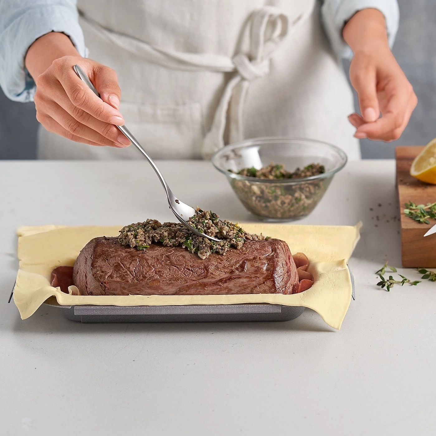 Person bereitet Fleisch zu. Sie gibt Pilzmasse auf das Fleisch. Kochprozess.