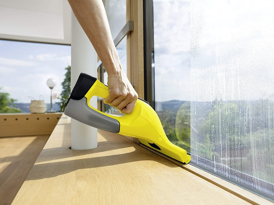 Person reinigt Fenster mit gelbem Fensterreiniger, Nahaufnahme