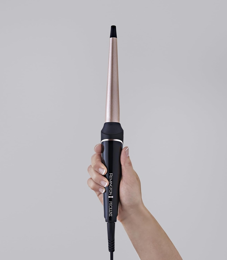 Lockenstab, der von einer Hand gehalten wird, mit dem Markennamen Remington Proluxe.
