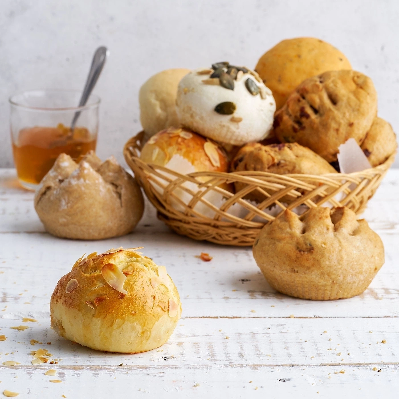 Korb mit Brötchen, Glas Marmelade, Holzuntergrund, Nahaufnahme, Essen
