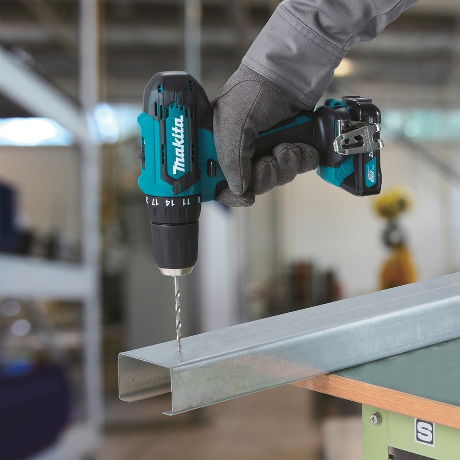 Makita-Bohrmaschine bohrt Metall. Handwerker mit Handschuh. Bohrer in Aktion. Werkzeug.