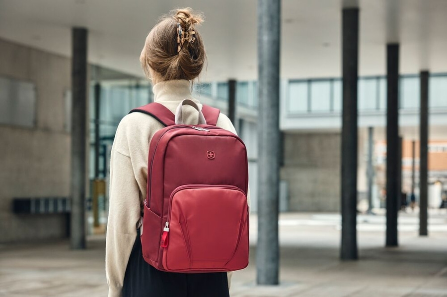Rote Tasche auf dem Rücken einer Person vor einem Gebäude.