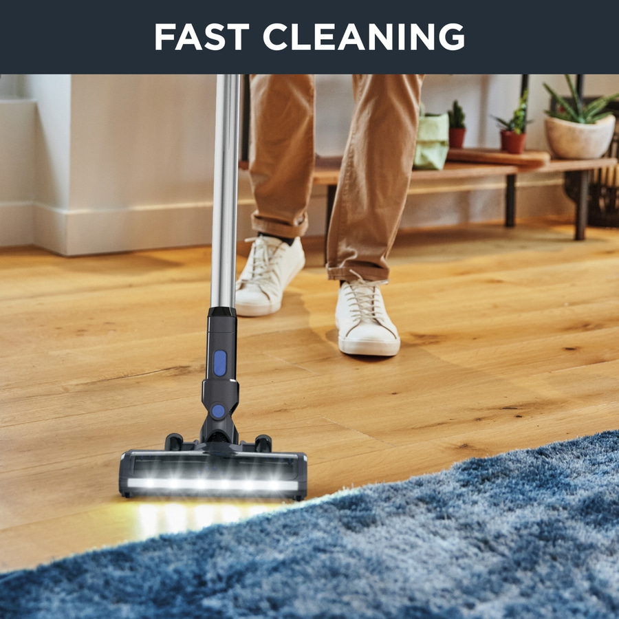 Staubsauger auf Holzboden mit der Aufschrift 'FAST CLEANING' und Person im Hintergrund