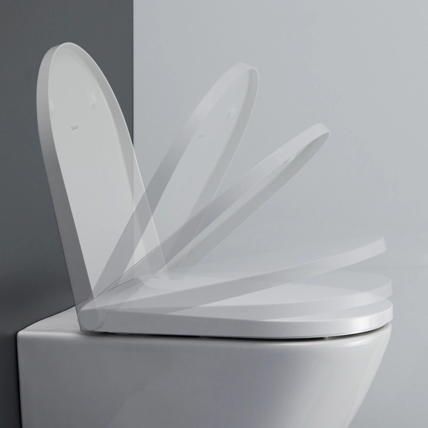 Weißer Toilettendeckel hebt sich in mehreren Stellungen vom Hintergrund ab.