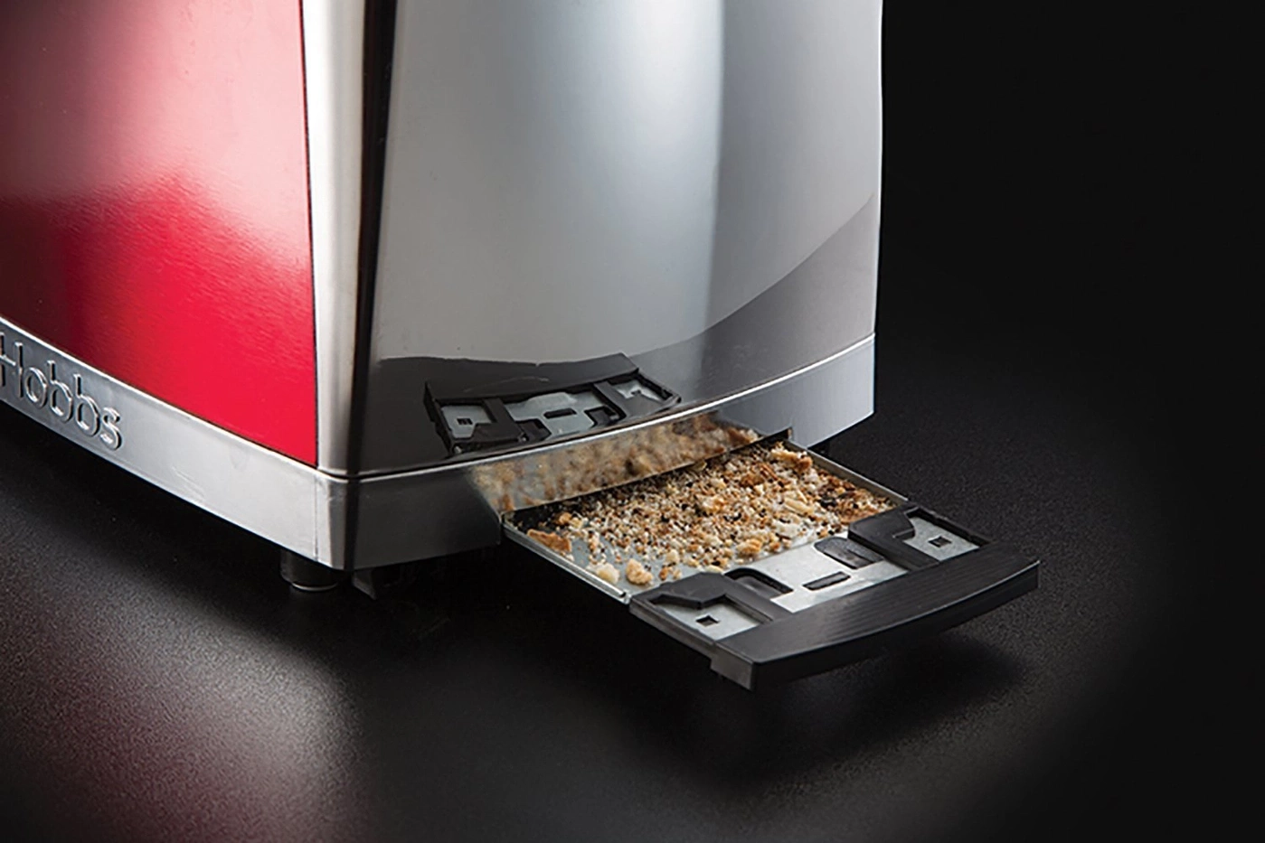 Nahaufnahme eines Toasters mit herausgezogener Krümelschublade, gefüllt mit Brotkrümeln.