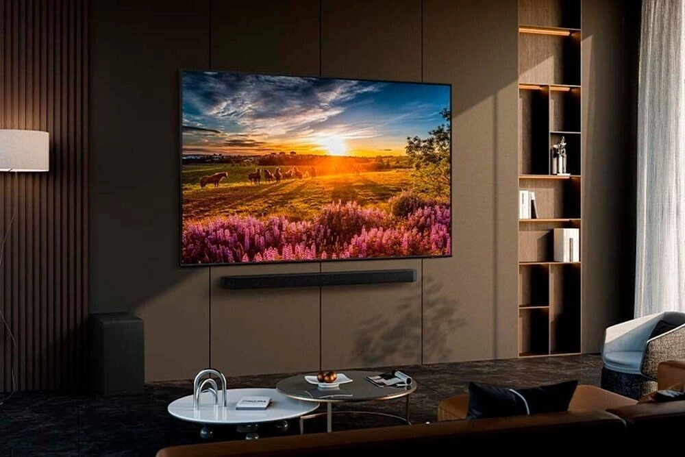 Wohnzimmer mit Fernseher, Sofa und Bücherregal.