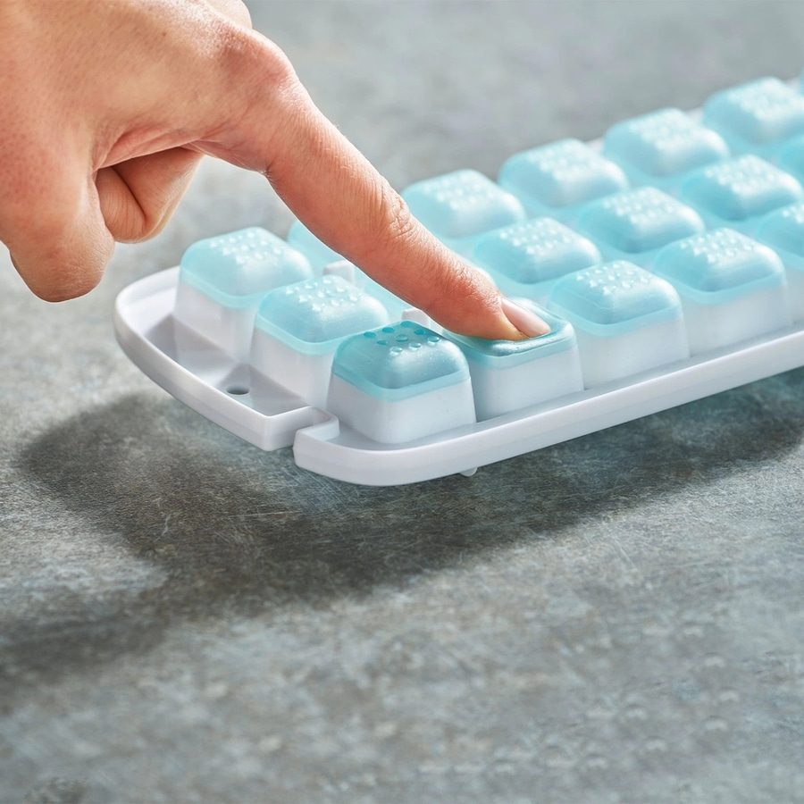 Hand drückt auf Eiswürfelbehälter, blau und weiß, auf grauem Hintergrund
