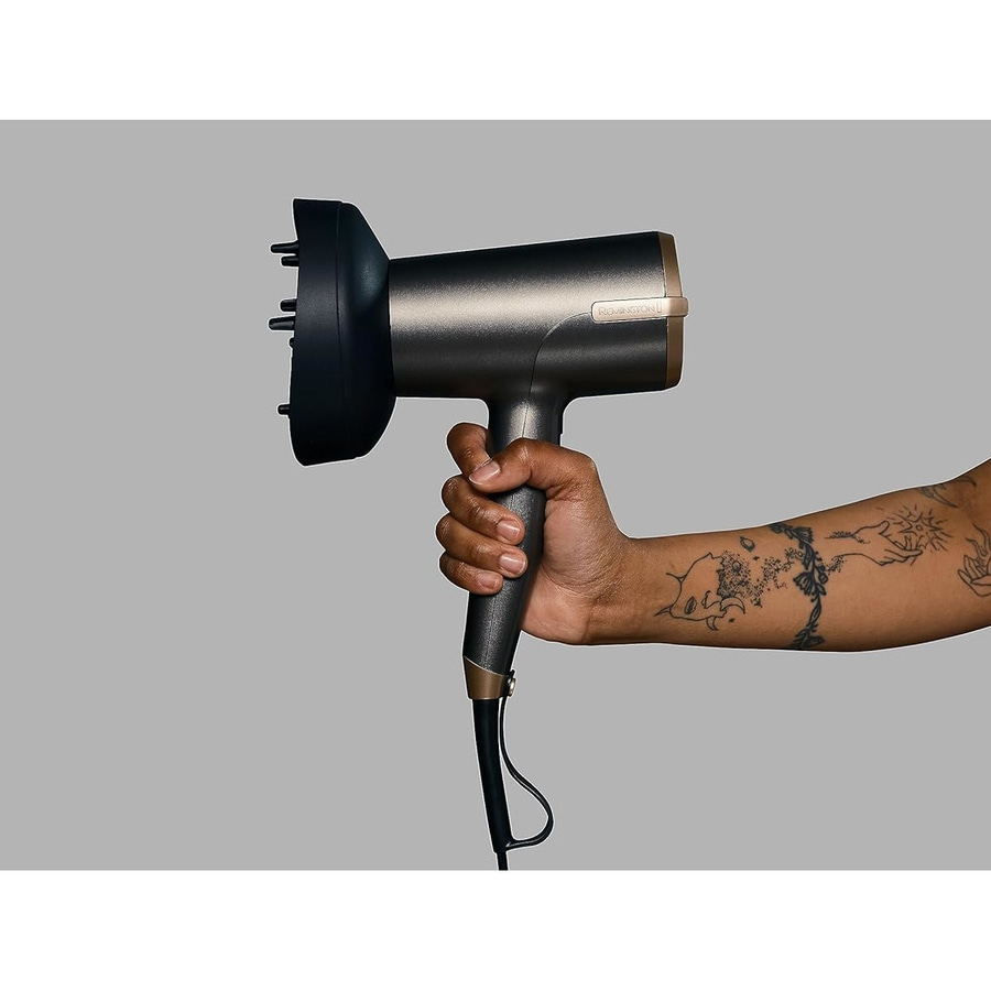 Ein Arm hält einen schwarzen Haartrockner mit Diffusor-Aufsatz.