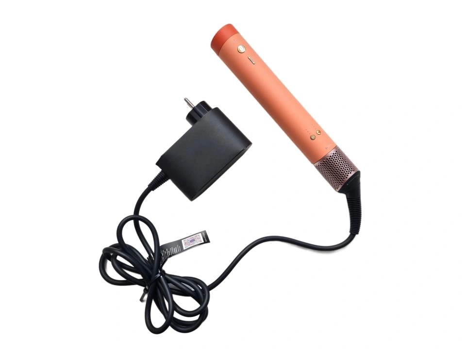 Ein korallenfarbener Haartrockner mit schwarzem Ladegerät und Kabel