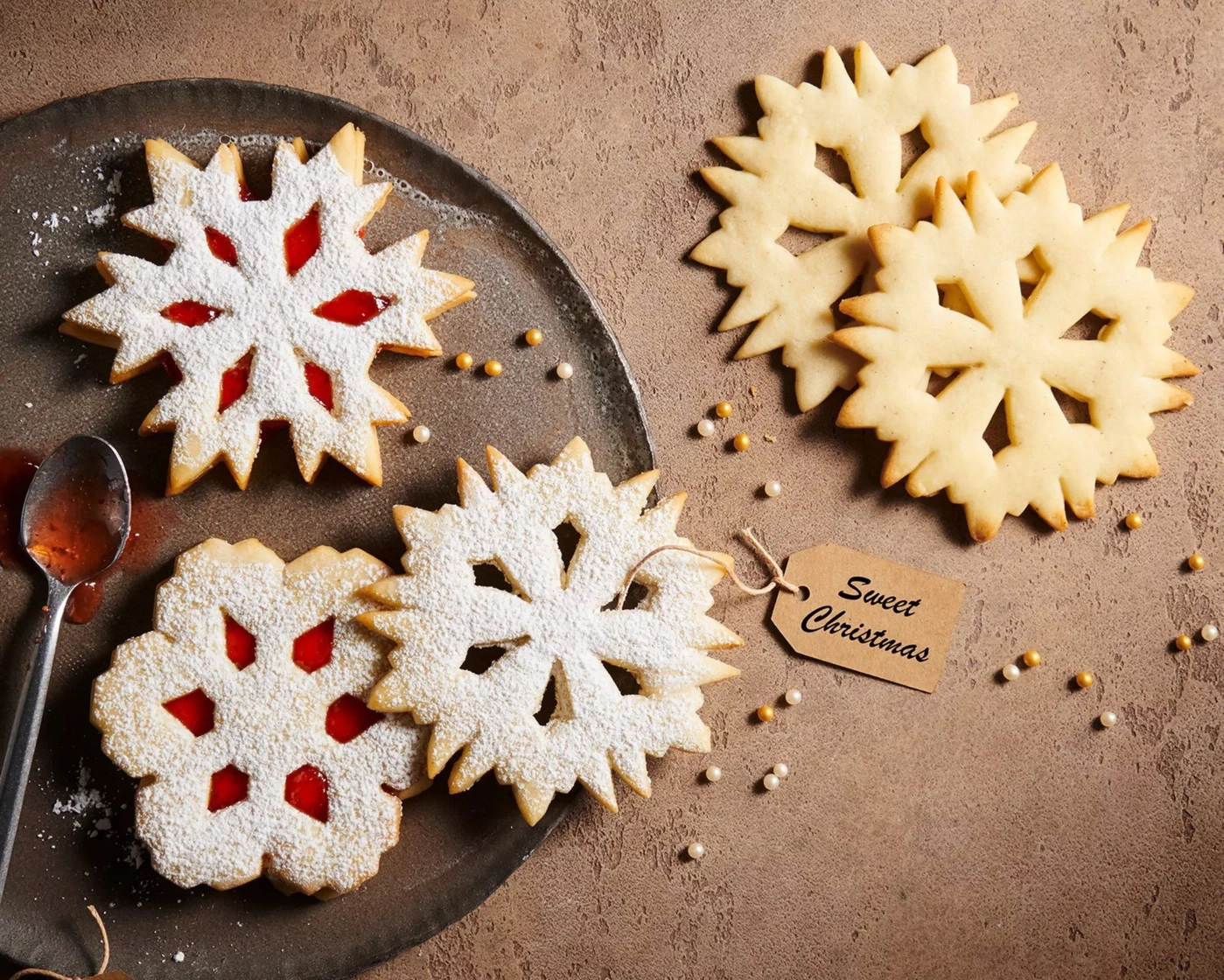 Weihnachtsplätzchen mit Puderzucker und Marmelade auf einem Teller