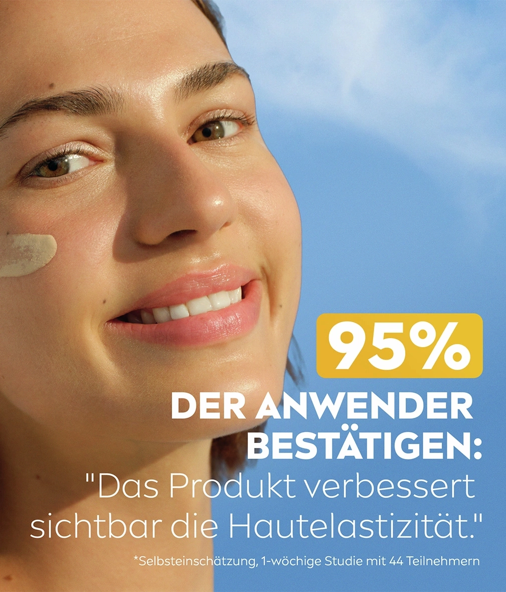 Ein Lächeln einer jungen Frau mit Sonnenschutz auf der Wange vor blauem Himmel.